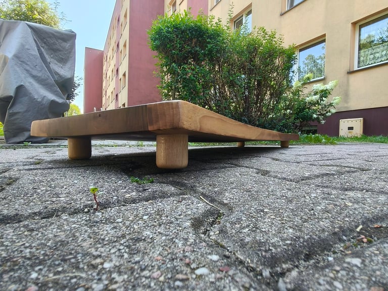 Wooden bench on gravel ground with residential buildings and green shrubs in background